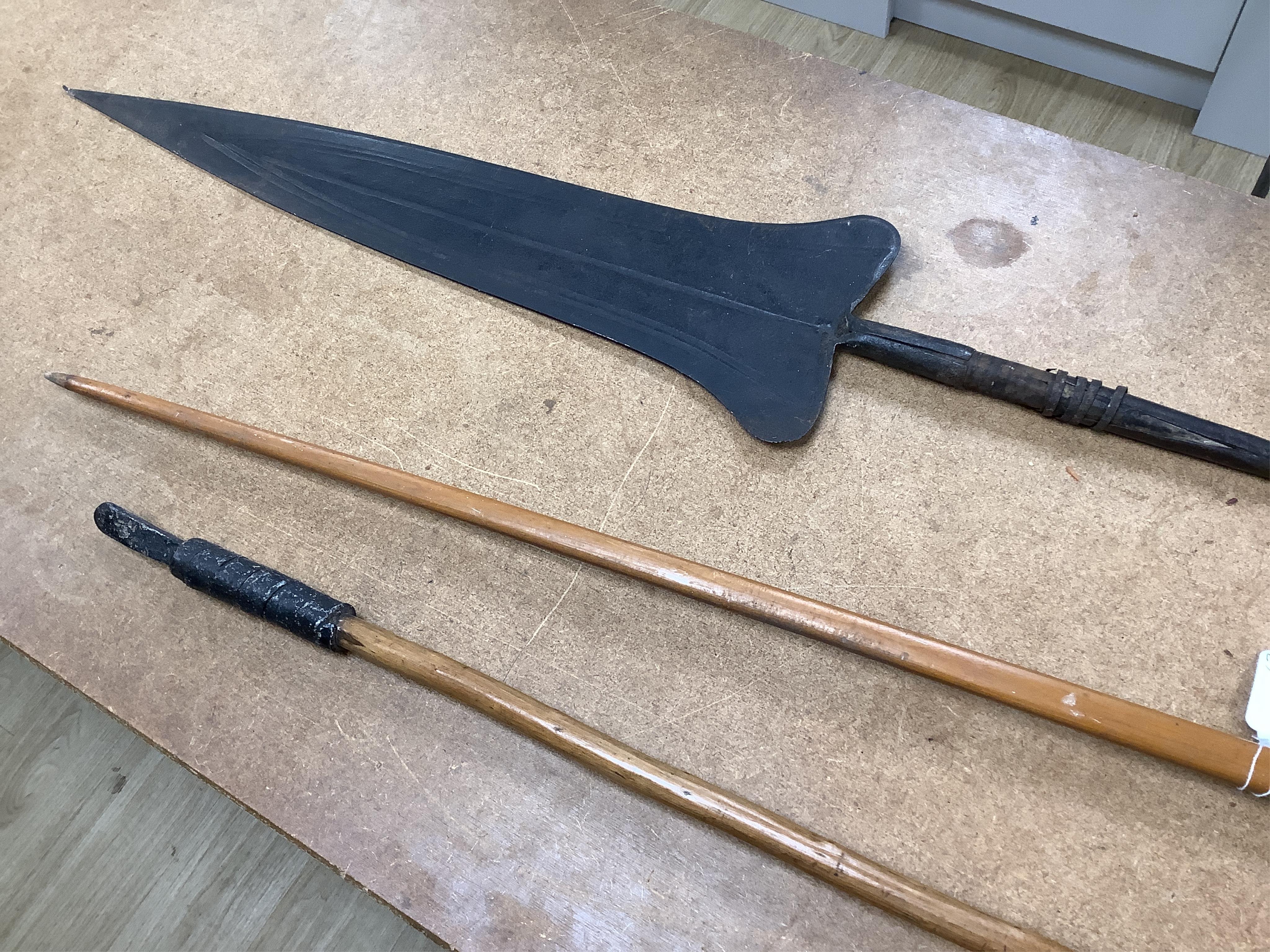 A collection of tribal spears, a fish hook, a cased snooker cue, etc.